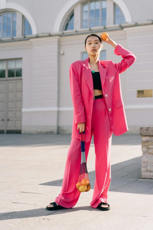 a woman wearing a pink suit is holding a bag