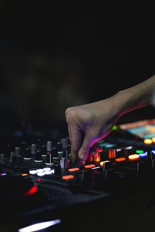 person touching the music mixer on a dj board