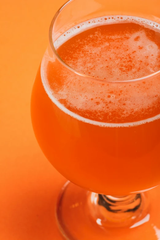 the glass of orange beer has a light foamy substance on it