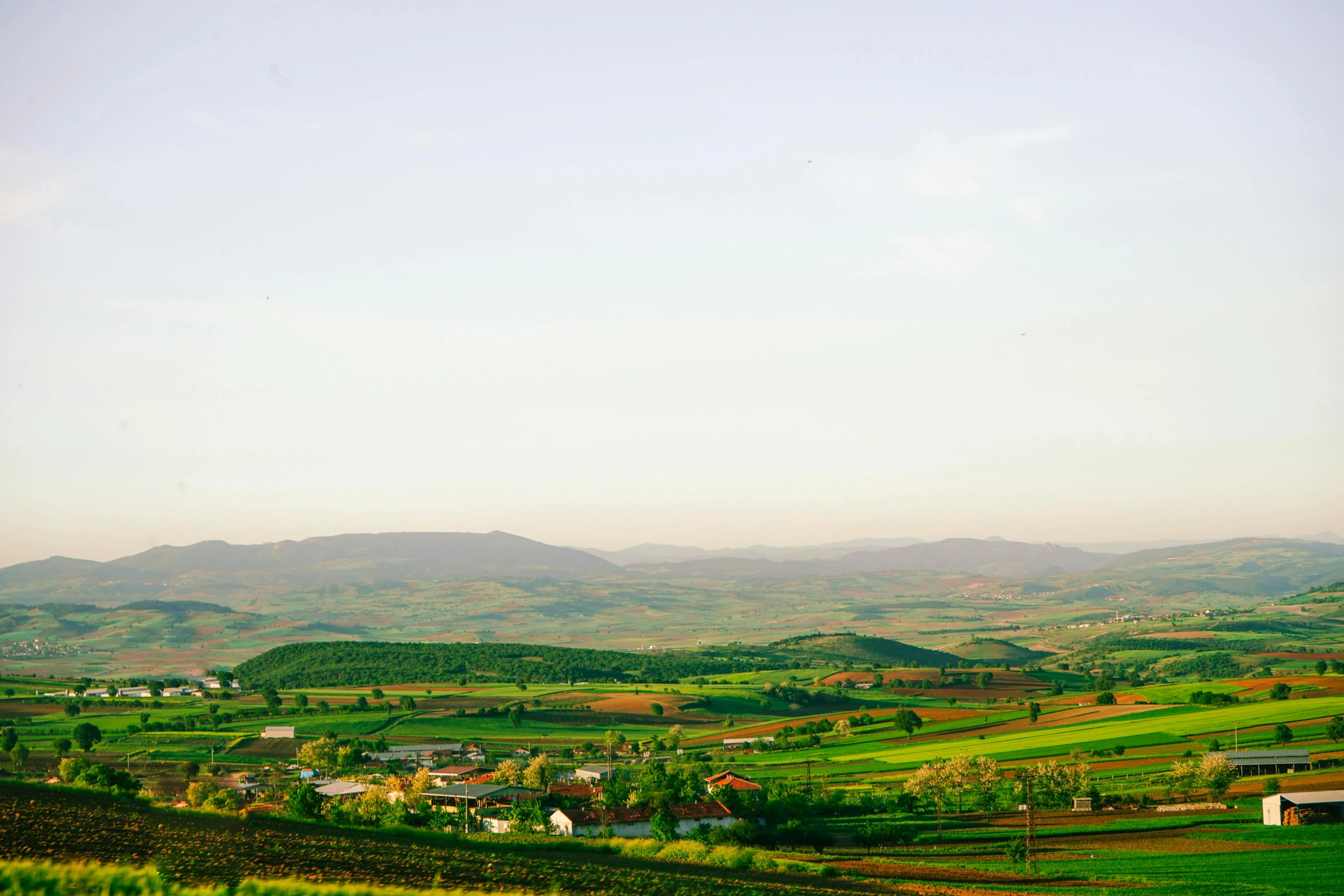 a landscape scene with rolling hills and fields in the foreground