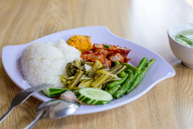 a plate of food and a bowl with rice on a wooden table