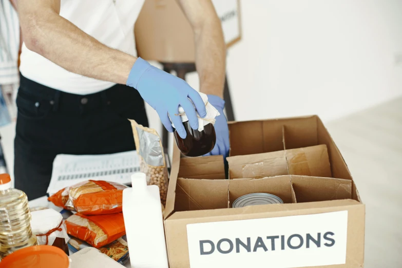 a man with gloves on pouring food into a box