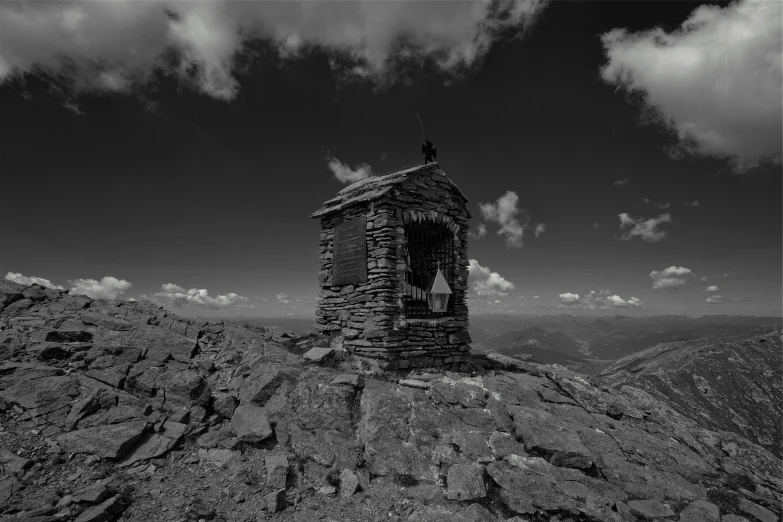 a black and white po of a hut on the top of a mountain