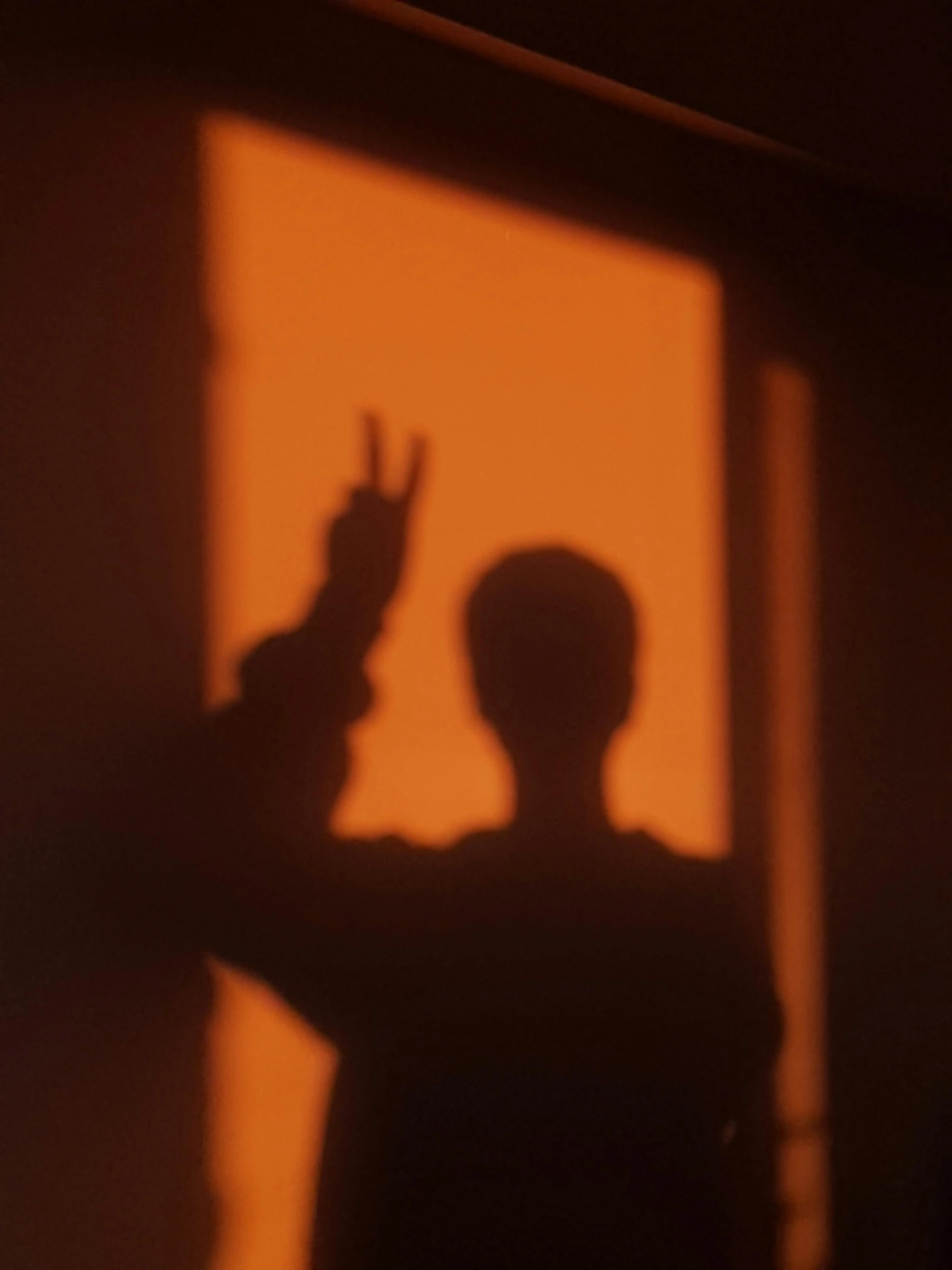 a shadow of a child's hands holding an alarm clock in front of a window