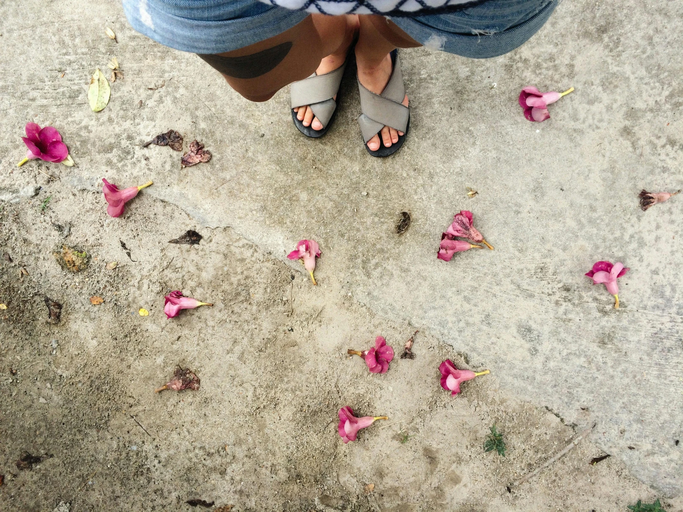 the girl stands in her sandals on the sidewalk