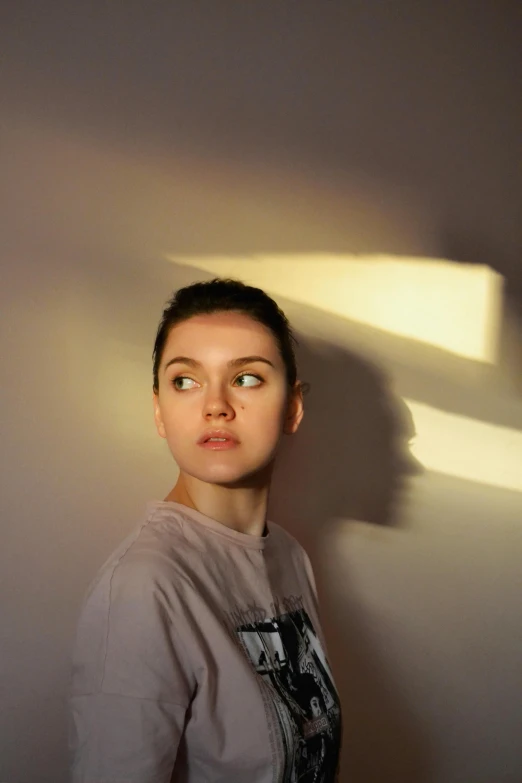 a woman standing in front of a white wall with the light coming through her eyes