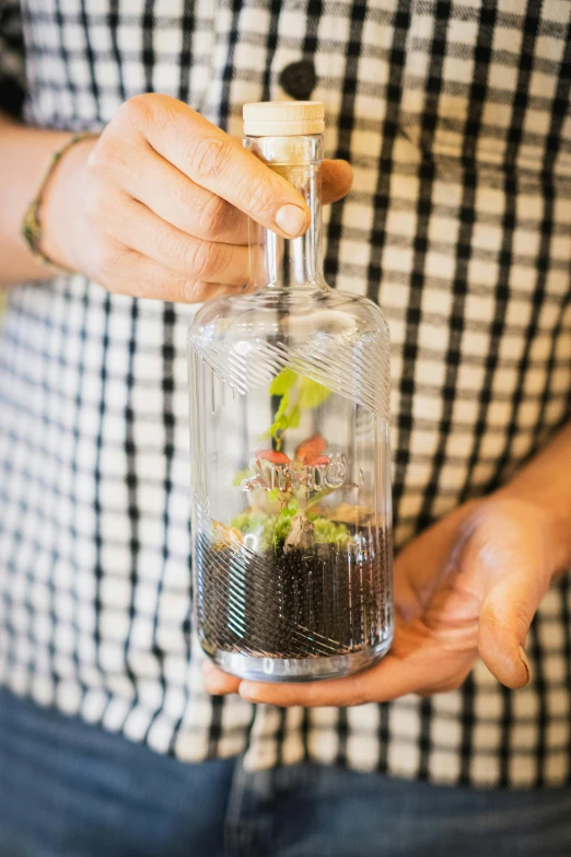 man holding a bottle with plants inside of it