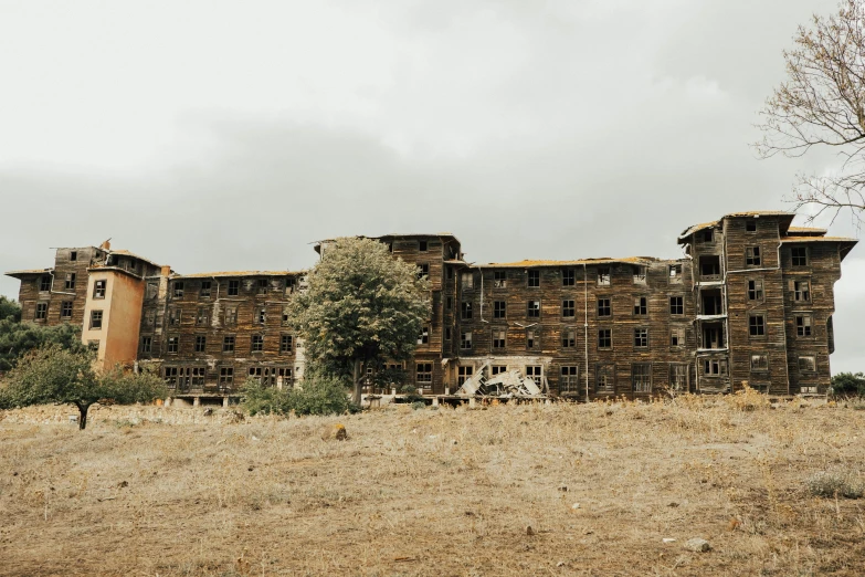 an abandoned building on a grassy hill under a cloudy sky