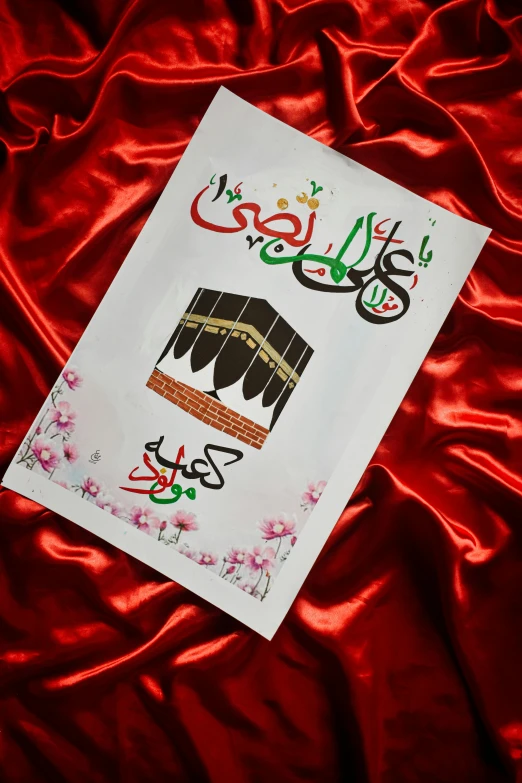 a white paper with red floral design in arabic on top of a red blanket