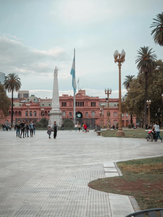 people in a courtyard next to large pink building