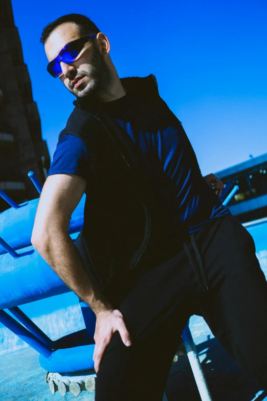 a man sitting on a bench in sunglasses and a vest