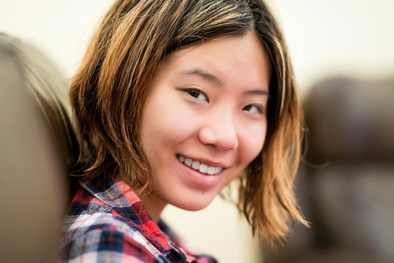 a smiling woman with a plaid shirt looking at the camera