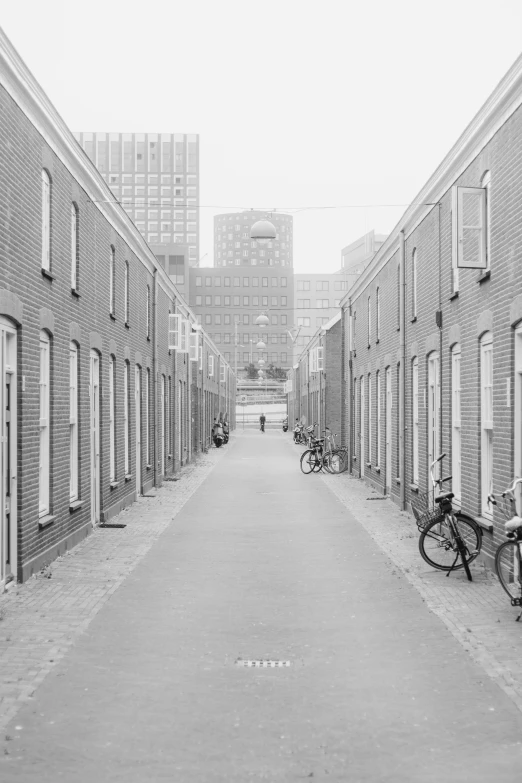 an alley with bicycles on the sidewalks and two buildings