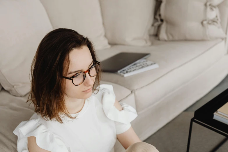 a lady is sitting with her book on a couch