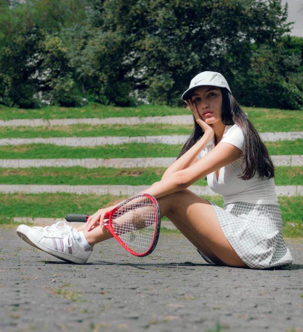 a woman with a tennis racket is sitting on a curb