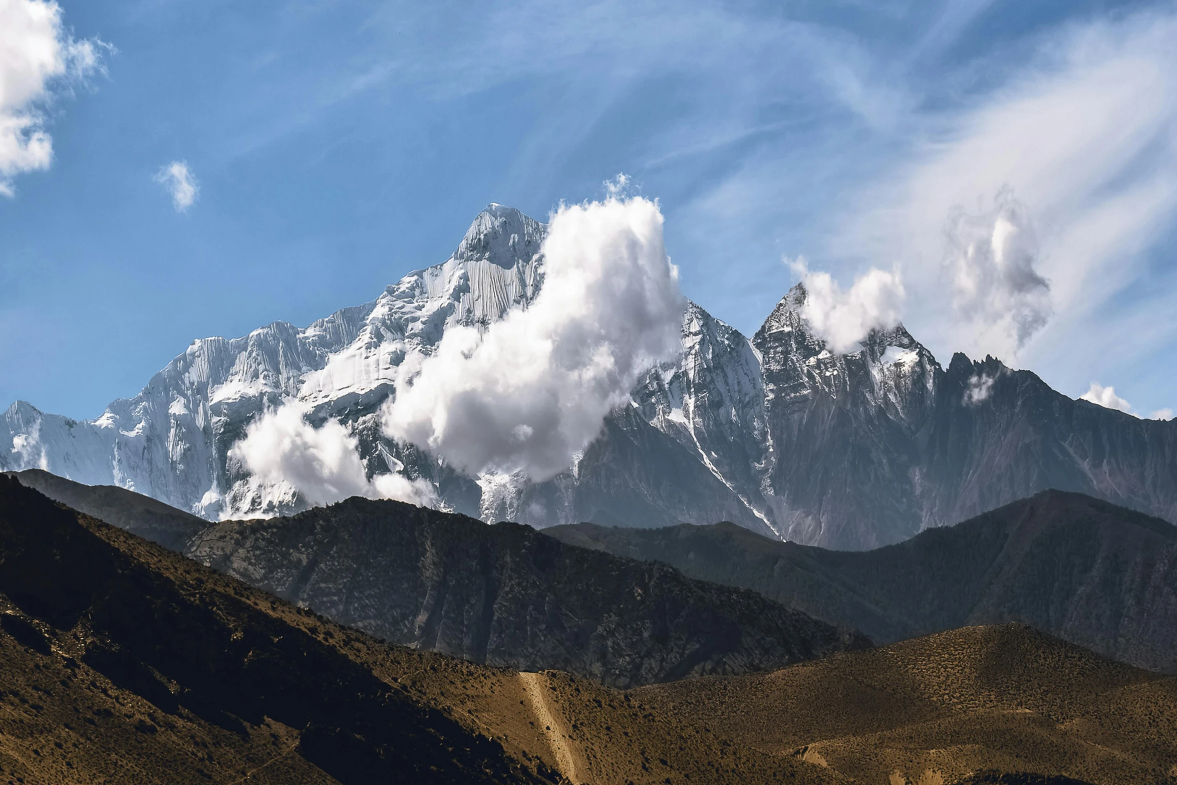 the mountains are covered with low clouds and brown brush