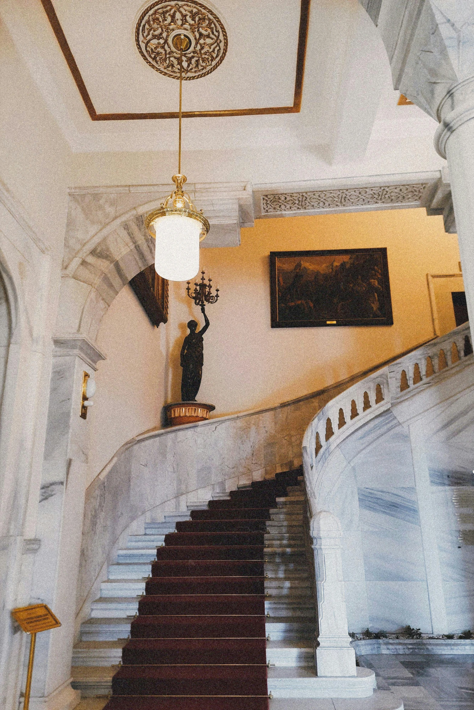 a hallway with a grand staircase, and artwork on the wall