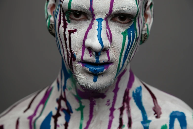 a man with white face paint, with streaks of color painted on his body