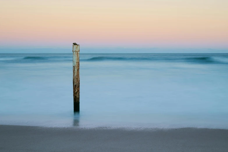 a tall pole on the beach near a body of water