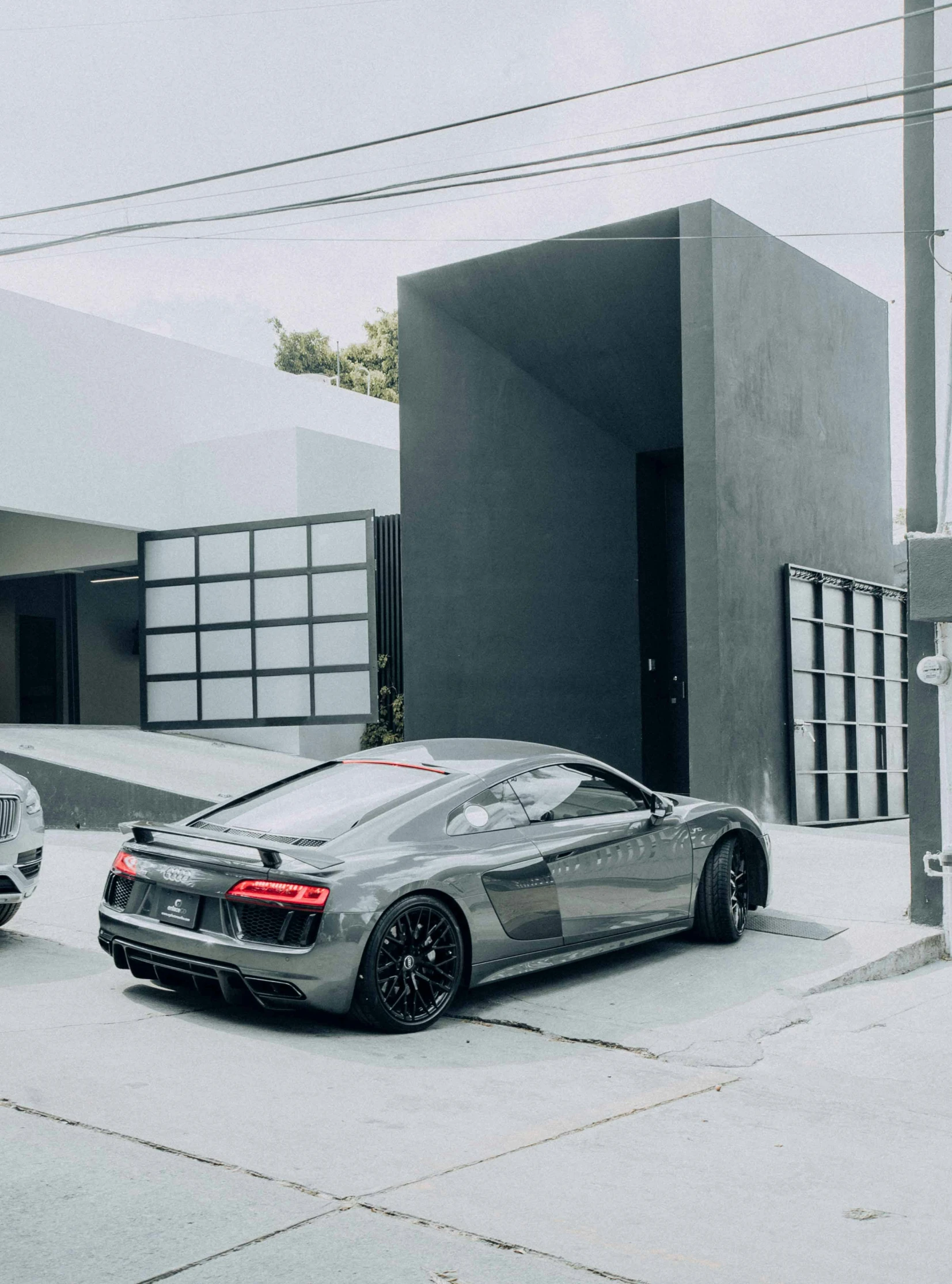 two silver and one black sports cars in a parking lot