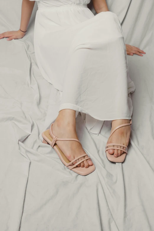 a woman is sitting on top of a bed wearing sandals