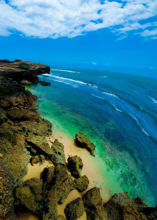 a beach on the shore with large rocks in front of it