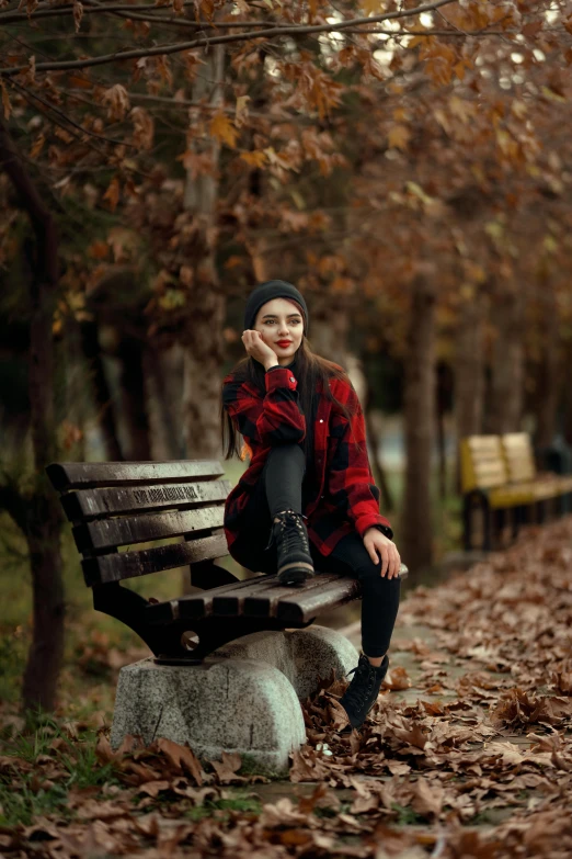 a beautiful young woman sitting on top of a bench