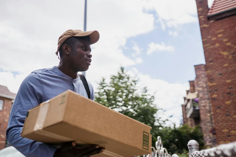 a man carrying a cardboard box across a street