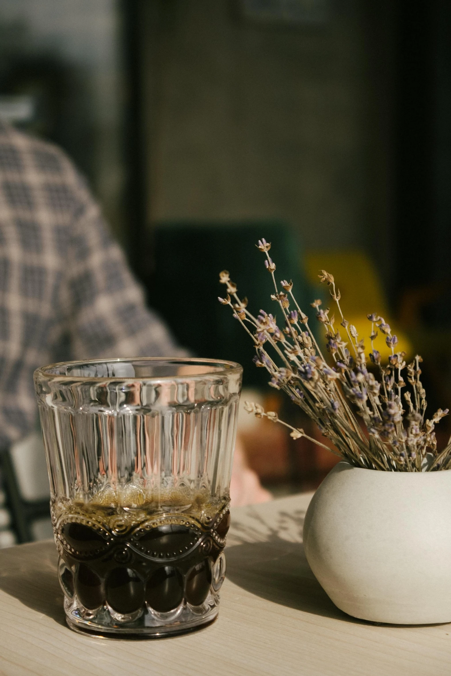 a table with a white glass on it next to a vase filled with flowers