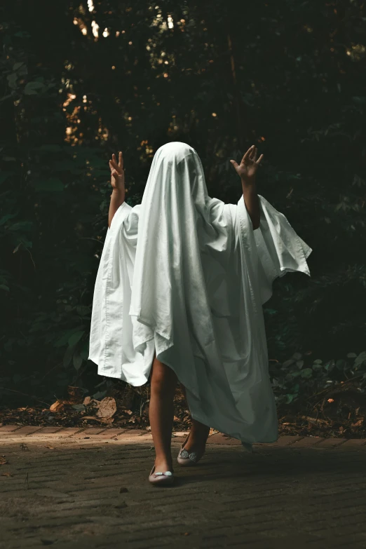 woman dressed in a white cloth walking through a forest