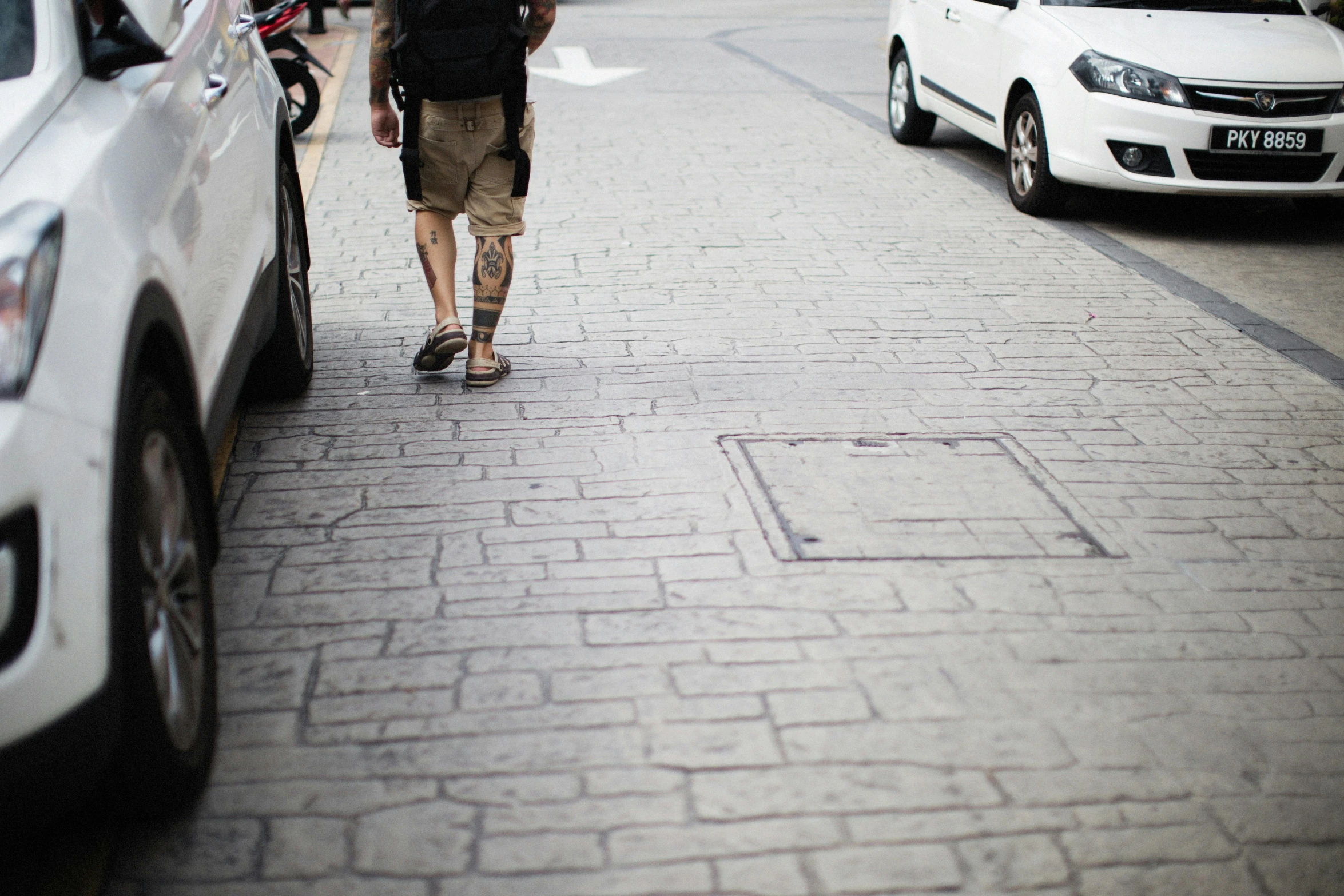 the boy is walking down the sidewalk with his bicycle