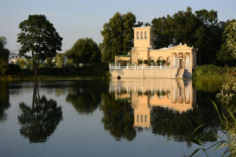 a building on the edge of a body of water with trees and buildings in the background