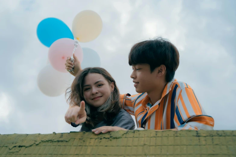 two asian people in a fence with balloons