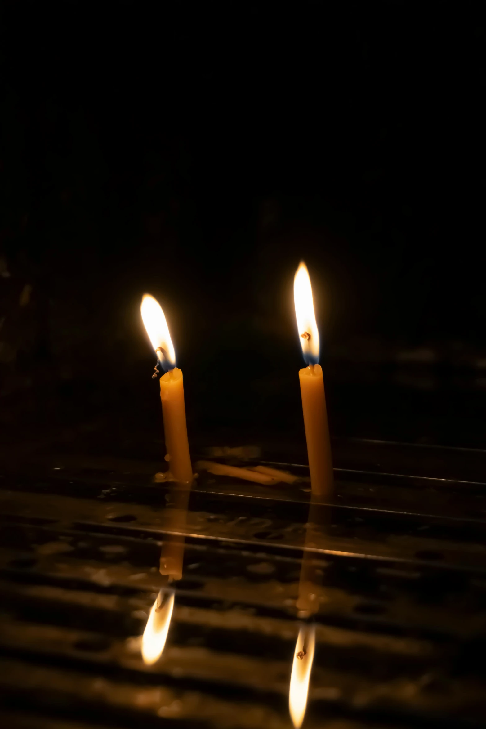 two candle lit in the dark on a surface