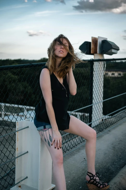 a woman sitting on top of a fence next to a body of water