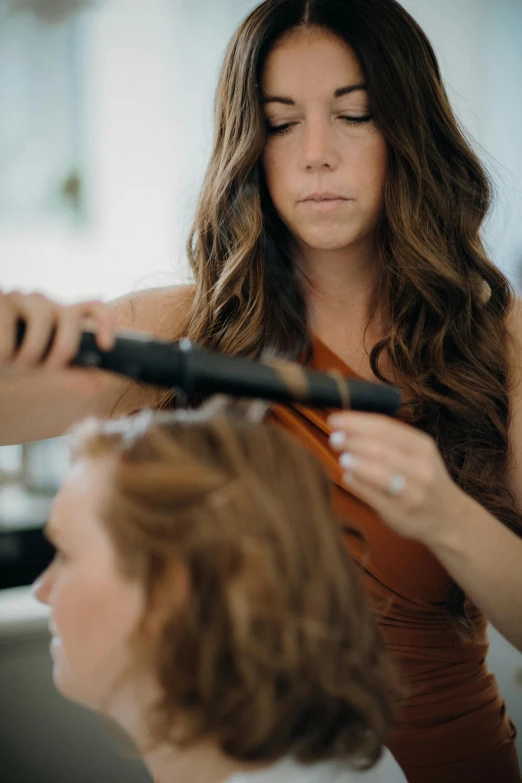 a woman holding a hair brush next to another woman with long hair