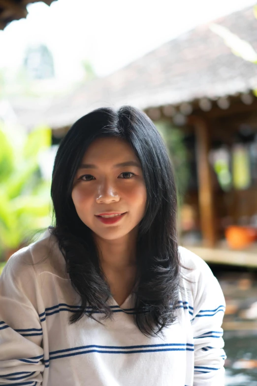 a young woman wearing a striped shirt is staring into the distance