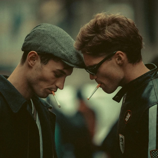 two men are holding a cigarette to their mouths