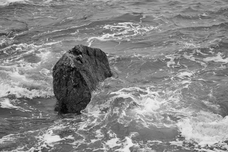 someone is standing in the water behind a rock