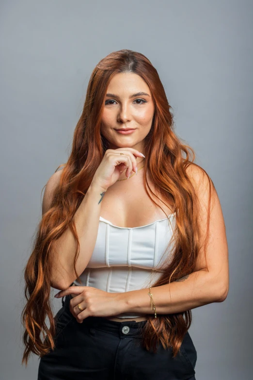 a beautiful young woman posing in front of a gray background