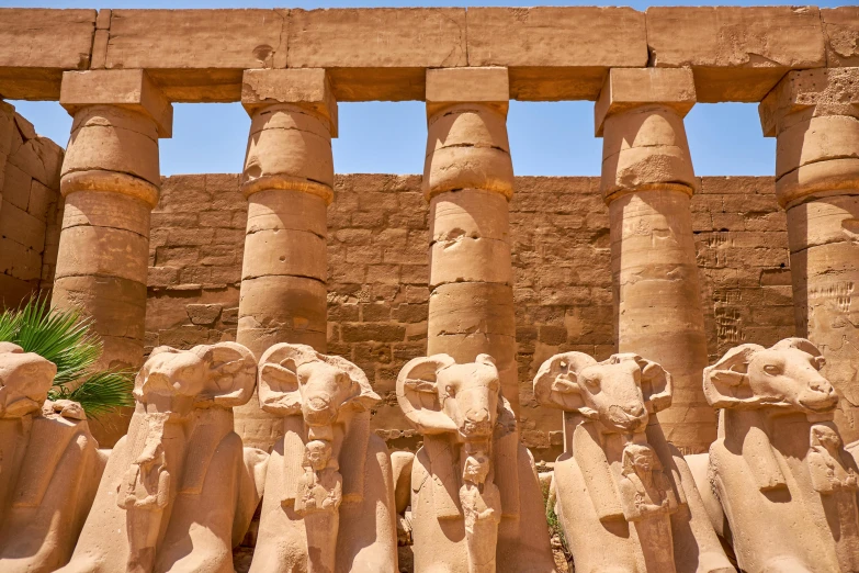 statues and heads in front of large pillars