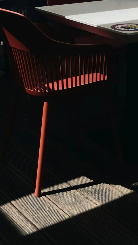 an orange chair sitting near a table outside