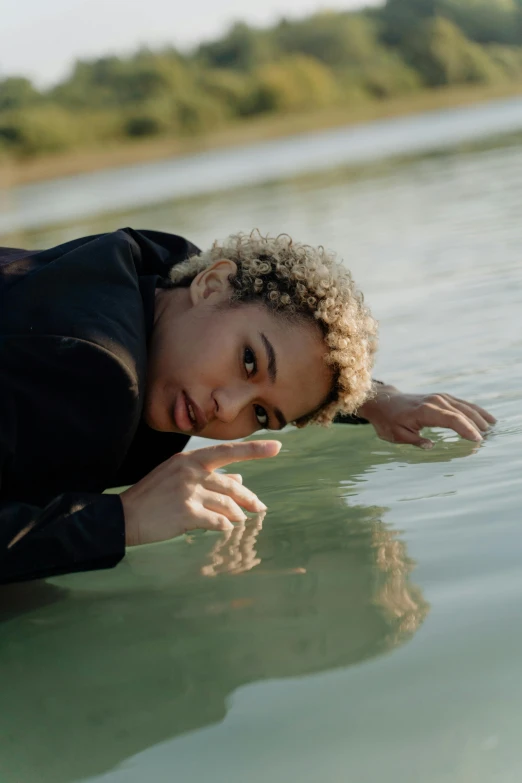 a woman leans down and looks at the camera in the water