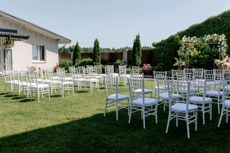 the lawn set up with white chairs is full of white flowers