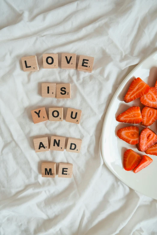 words made with scrabbles spelled in small letters, on a plate with strawberries