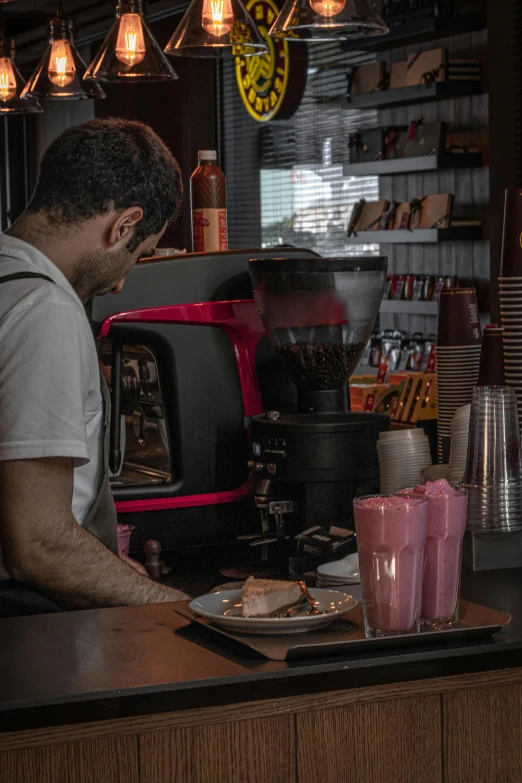 a man at the bar making drinks, while looking at his phone