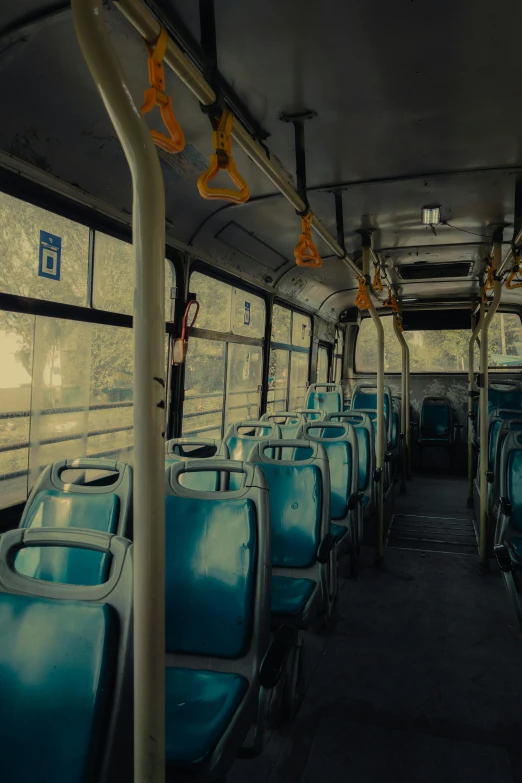 empty blue seats are on the bus with metal pipes