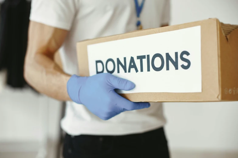 someone holds a donation box with the word donations