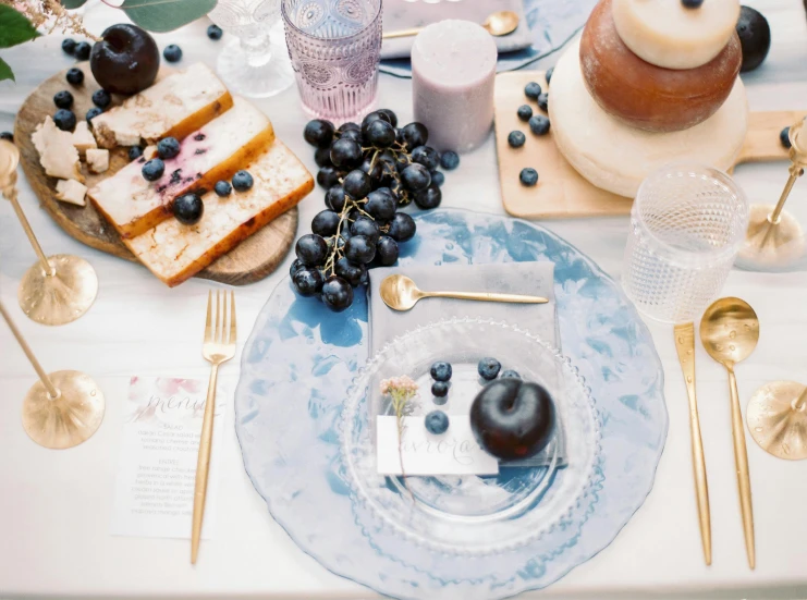 a plate with several desserts, fruit, and wine on it