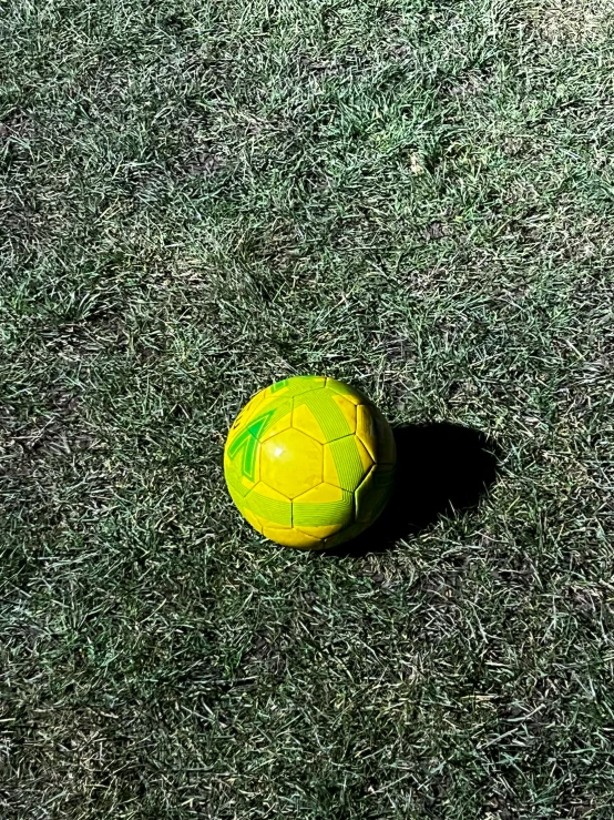 a yellow soccer ball with a yellow stripe in grass